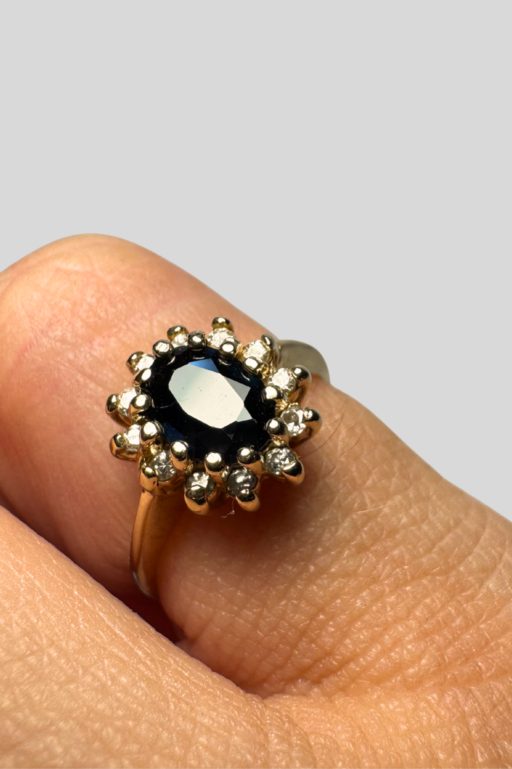 Gold ring with dark blue sapphire on grey background
