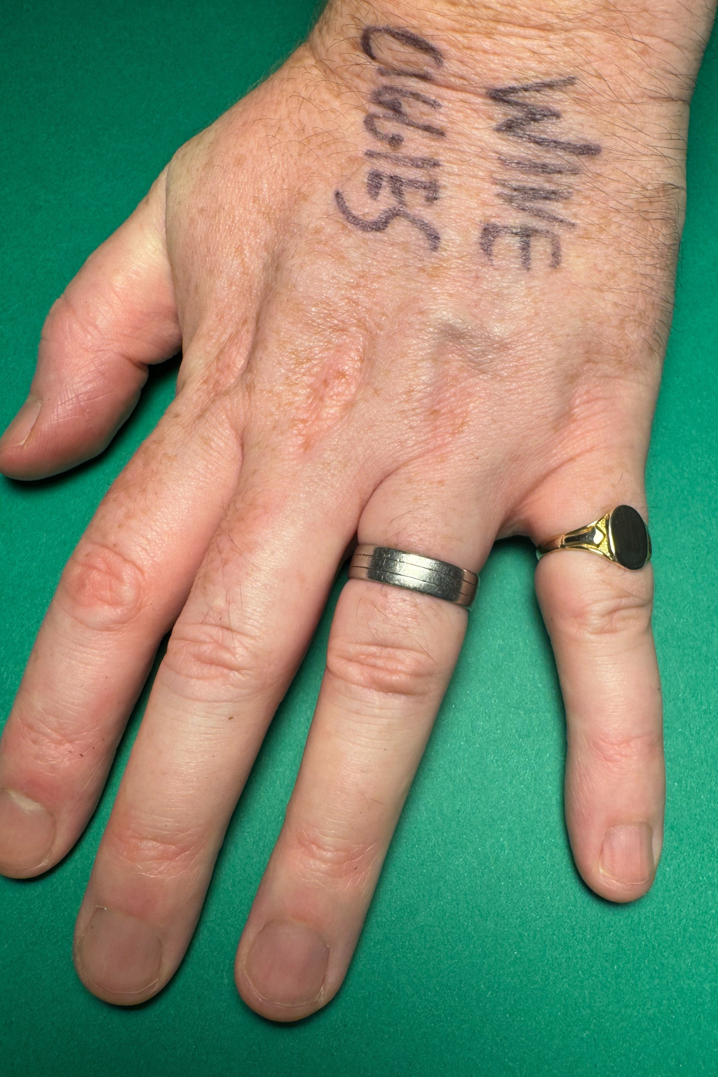 9 carat gold signet ring on male hand on green background with writing on hand