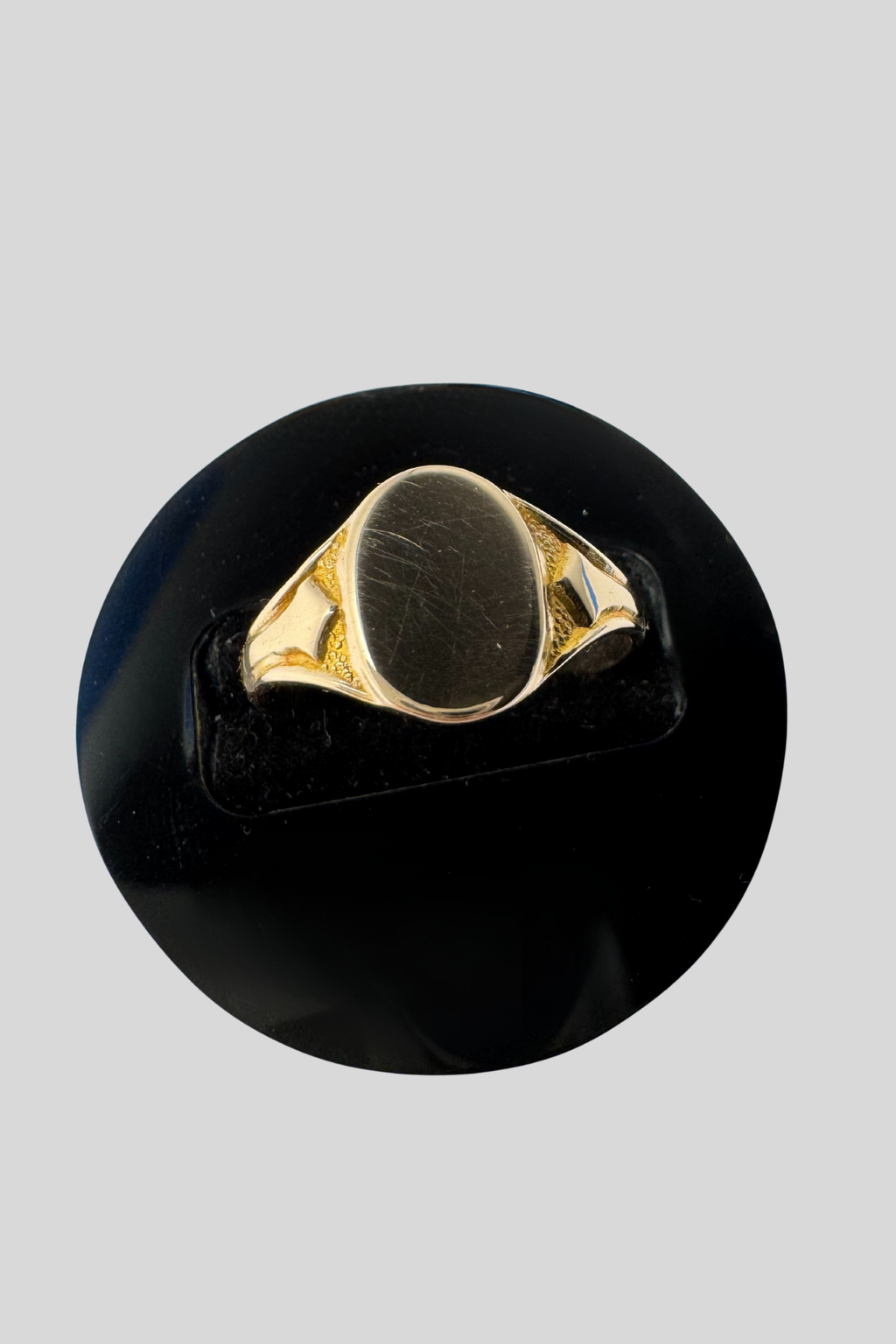 Solid 9 carat gold signet ring in ring stand on grey background